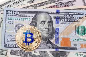 One Bitcoin on hundred dollars bill.