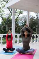 Mother and daughter meditating together in the porch