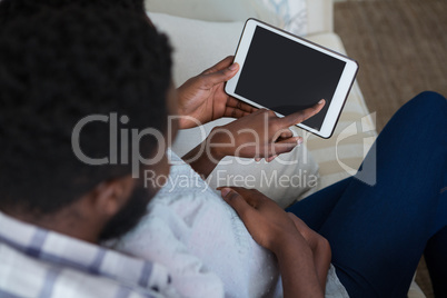 Couple using digital tablet in living room