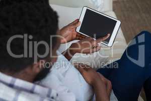 Couple using digital tablet in living room