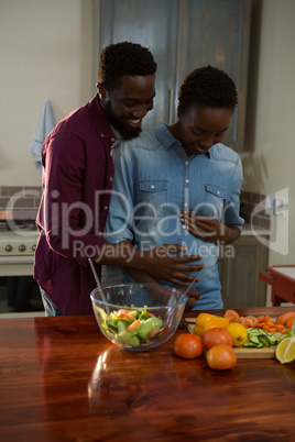 Man touching womans pregnant belly in the kitchen
