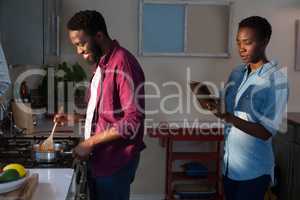 Woman digital tablet while man cooking in kitchen