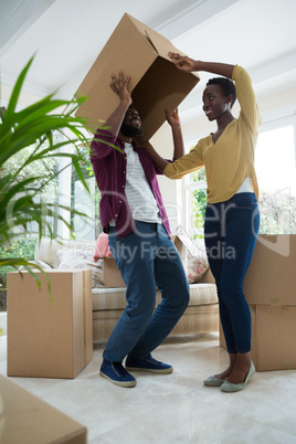 Couple playing with cardboard box in new house
