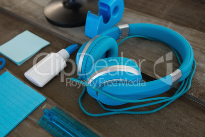 Headphone and various stationery on wooden surface