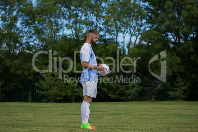 Football player holding soccer in the ground