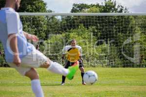 Soccer player kicking ball towards goal post