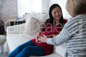 Female friends feeling the presence of baby in stomach