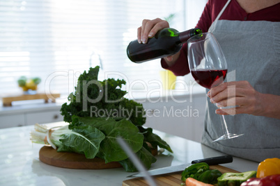 Mid section of woman having red wine at table