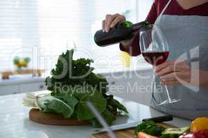 Mid section of woman having red wine at table