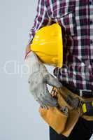 Architect with tool belt and holding hard hat against white background