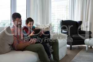 Father and son using digital tablet in living room
