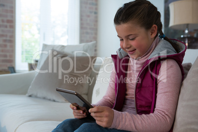 Cute girl using digital tablet in living room