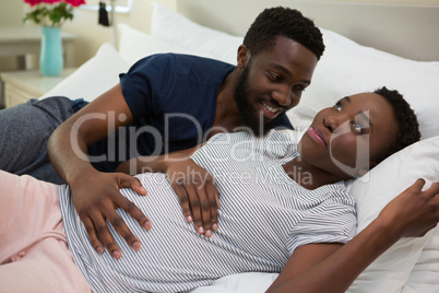 Man touching woman stomach in bedroom