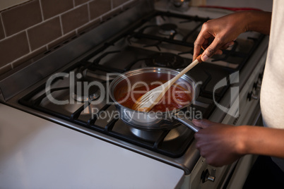Mid section of woman cooking food in kitchen