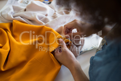 Female fashion designer stitching cloth with needle