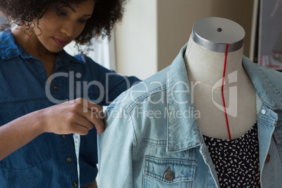 Female designer measuring the length of denim on mannequin