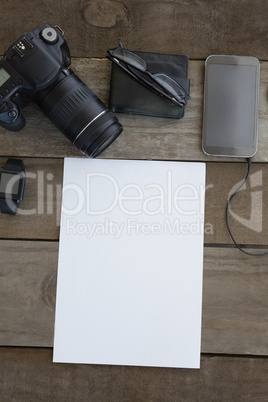 Digital camera, wallet, spectacles, smartwatch, mobile phone and blank paper on wooden surface