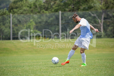 Football player kicking the soccer on the football ground