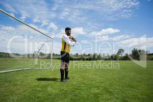 Goalkeeper holding football in front of goal post