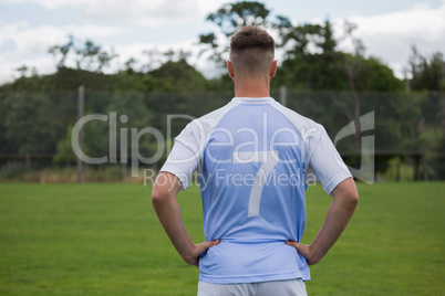 Football player standing with hand on hips in ground