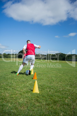 Soccer player dribbling through cones