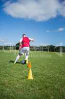 Soccer player dribbling through cones