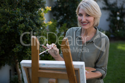 Portrait of beautiful woman painting on canvas