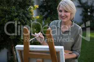 Portrait of beautiful woman painting on canvas