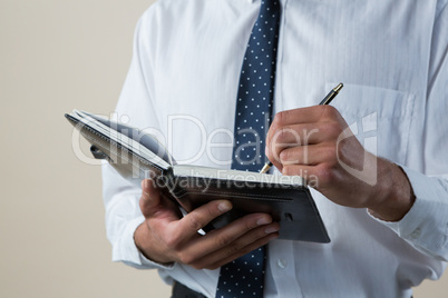 Executive writing on diary against white background