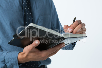 Executive writing on diary against white background