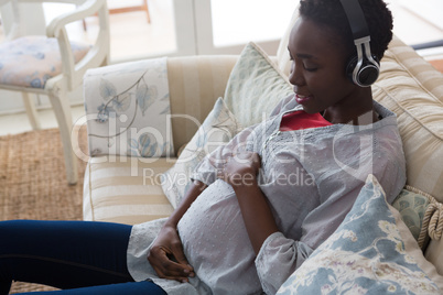 Pregnant woman listening music on headphones