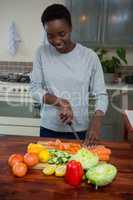 Beautiful woman chopping vegetables in kitchen