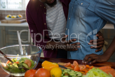 Man touching womans pregnant belly in the kitchen