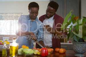 Couple having wine while chopping vegetables