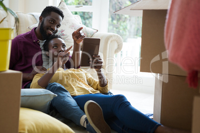 Couple using digital tablet while relaxing in new house