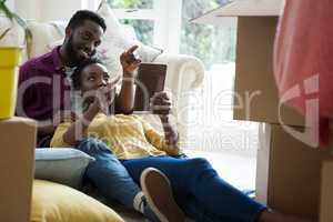 Couple using digital tablet while relaxing in new house