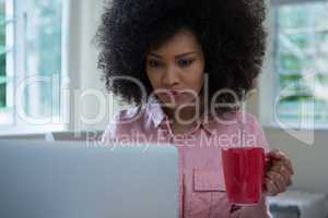 Woman using laptop while having coffee