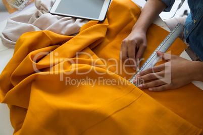Mid section of female fashion designer marking on fabric