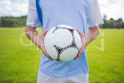 Football player holding soccer in the ground