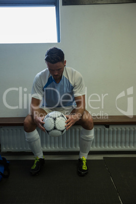 Football player sitting on bench in changing room