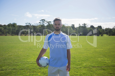 Football player holding soccer in the ground