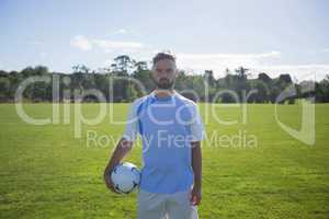 Football player holding soccer in the ground