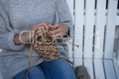 Mid section of woman knitting wool