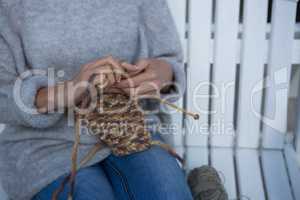 Mid section of woman knitting wool