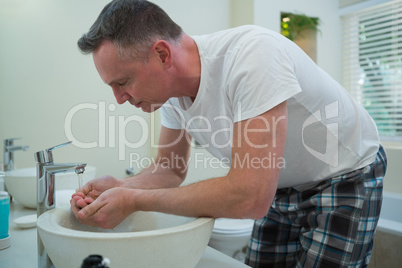 Man spraying water on his face after shaving in the bathroom