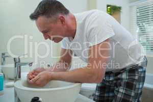 Man spraying water on his face after shaving in the bathroom