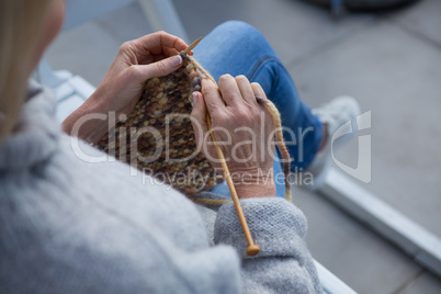 Woman knitting wool in porch