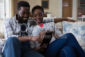 Couple using digital tablet in living room