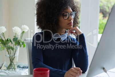 Thoughtful woman working on desktop pc at desk