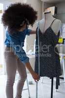 Female designer measuring the length of dress on mannequin